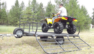 A man riding an atv on top of a trailer.