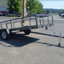 A trailer with a ramp attached to it in the middle of a parking lot.